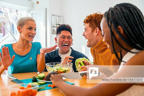 Porträt einer Gruppe von Freunden bei der Zubereitung vegetarischer Gerichte. Sie bereiten den Salat vor und haben Spaß im Haus