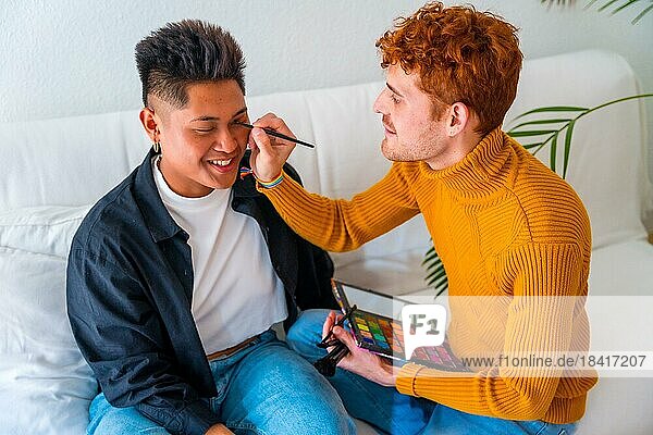 Beautiful gay couple doing makeup and having fun being romantic indoors at home  lgbt concept  real people  real couple
