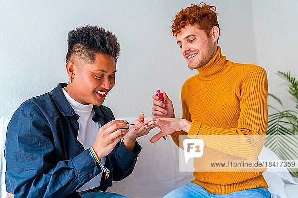 Beautiful gay couple putting on makeup  painting their nails and smiling being romantic indoors at home  lgbt concept