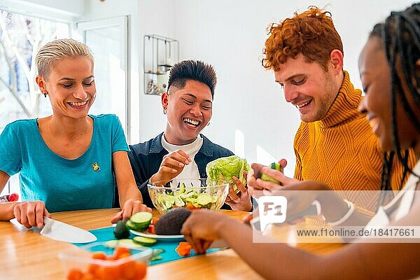 Porträt einer Gruppe von Freunden bei der Zubereitung vegetarischer Gerichte. Sie bereiten den Salat vor und haben Spaß im Haus