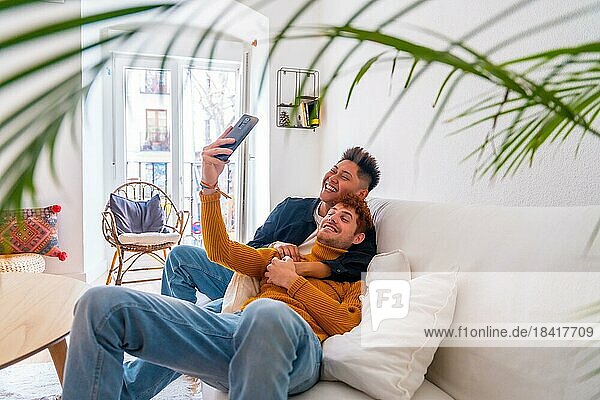 Beautiful gay couple being romantic at home on the sofa  taking a selfie  lgbt concept