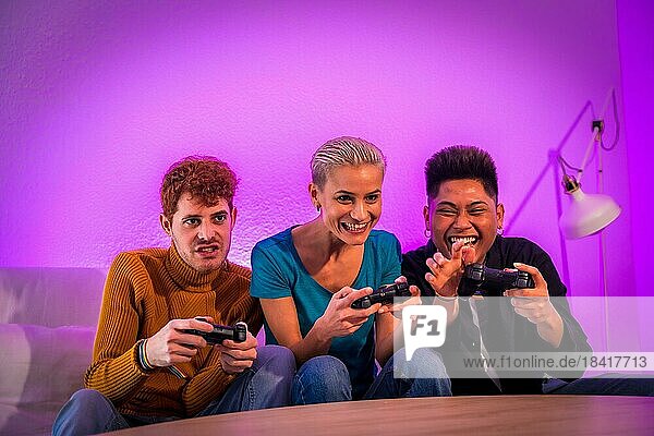 Group of young friends playing video games together on the sofa at home  purple led  having fun pushing