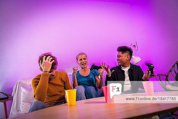 Gruppe junger Freunde  die zusammen auf dem Sofa zu Hause Videospiele spielen  lila geführt  Frau gewinnt