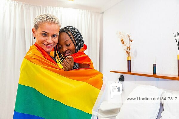 Schöne lesbische Paar umarmt mit Regenbogenflagge drinnen zu Hause  lgbt Konzept