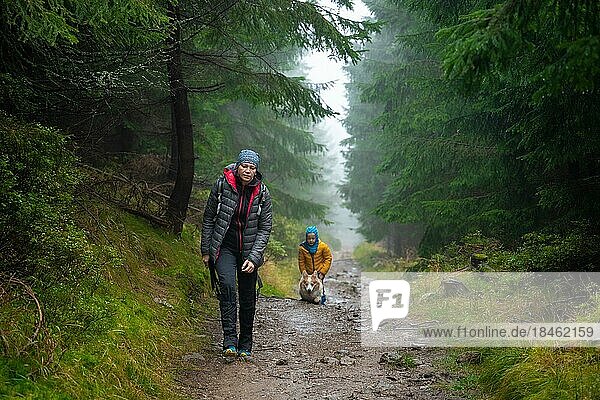 Mum and her little son go on a mountain trail in wet autumn weather. They are accompanied by a dog. Polish mountains  Poland  Europe