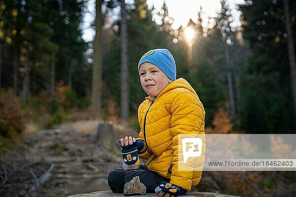 Little kid is sitting on a big stump on the mountain trail  eating. Fall season  Poland  Europe