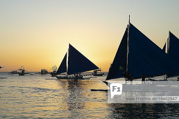 Traditionelle Segelboote auf der Tablas-Straße  hinten der Sonnenuntergang vom Angol Beach  Insel Boracay  Inselgruppe Visayas  Philippinen  Asien
