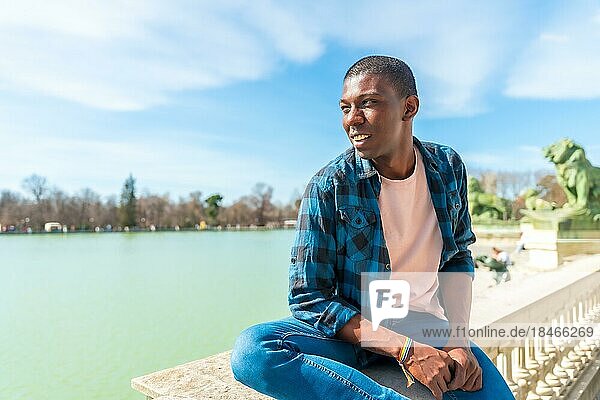 Porträt eines schwarzen ethnischen Mannes im Sommer an einem See  der sorglos seinen Sommerurlaub genießt