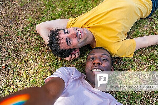 Portrait of a couple of multi-ethnic men in a park  lgbt concept  lying on the grass taking a selfie