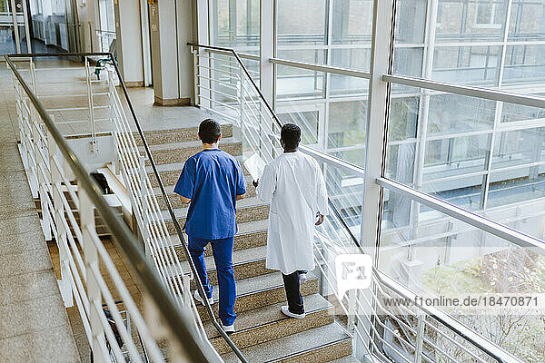 Hohe Winkel Ansicht der männlichen Arzt und Krankenschwester diskutieren  während die Bewegung auf der Treppe im Krankenhaus