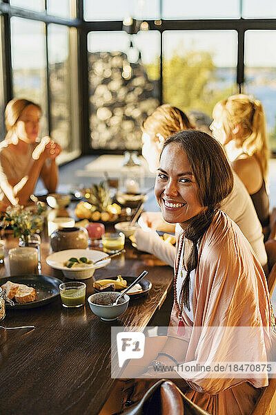 Porträt einer glücklichen Frau  die mit dem Frühstück auf dem Esstisch eines Rückzugszentrums sitzt