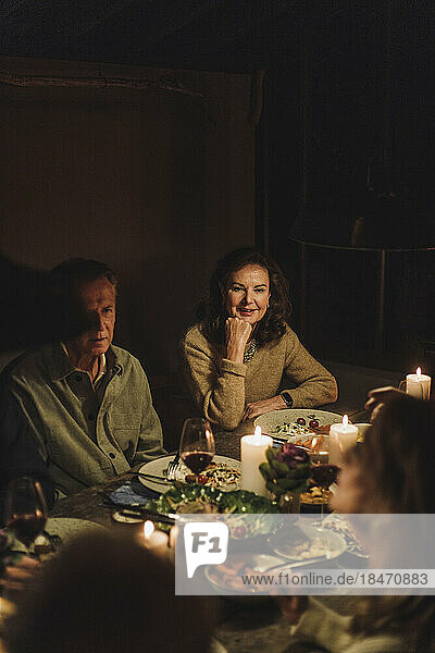 Älterer Mann und Frau sitzen bei Kerzenschein am Esstisch und feiern ein Abendessen