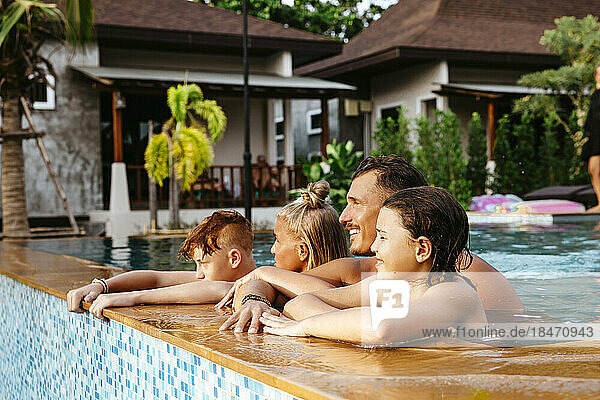 Eltern mit Kindern im Schwimmbad eines Ferienortes während der Ferien