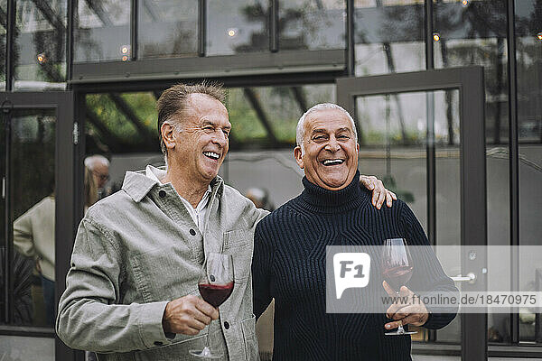 Glückliche männliche Freunde im Ruhestand mit Wein bei einer Dinnerparty