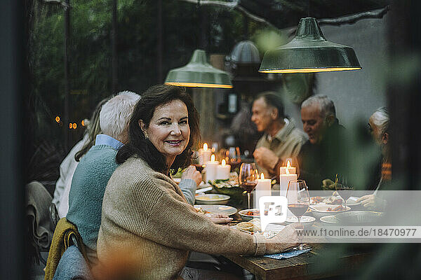 Porträt einer lächelnden älteren Frau  die sich mit Freunden bei einer Dinnerparty amüsiert