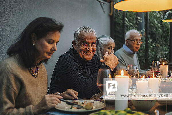 Porträt eines lächelnden reifen Mannes mit älteren Freunden während einer Dinnerparty