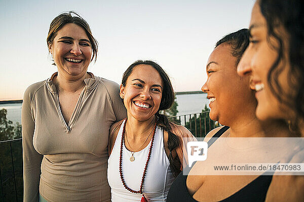 Multiracial happy female friends laughing together during sunset