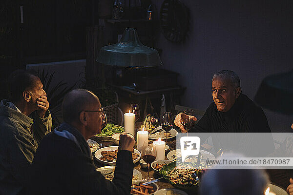 Männliche Freunde  die während einer nächtlichen Dinnerparty miteinander reden