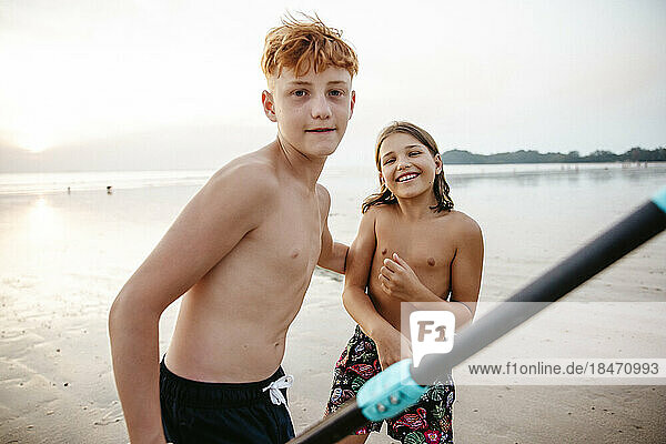 Portrait of sibling spending leisure time at beach during sunset