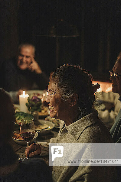 Side view of happy senior woman enjoying candlelight dinner party