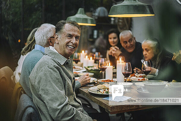 Porträt eines glücklichen älteren Mannes mit Freunden während einer Dinnerparty