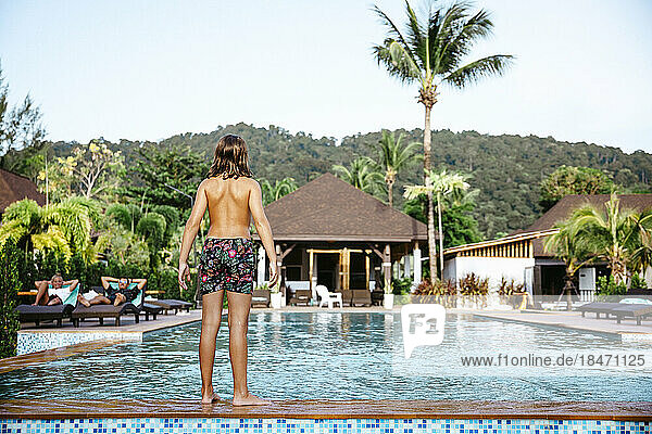 Rückansicht eines Mädchens ohne Hemd  das am Pool in einem Ferienort steht