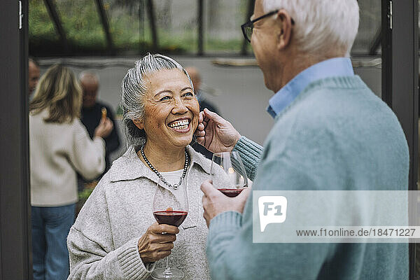Älterer Mann berührt das Gesicht einer glücklichen Freundin bei einer Dinnerparty