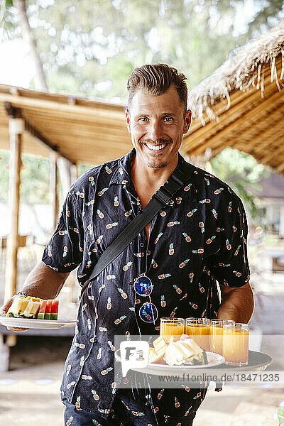 Porträt eines lächelnden männlichen Touristen beim Frühstück in einem Ferienort
