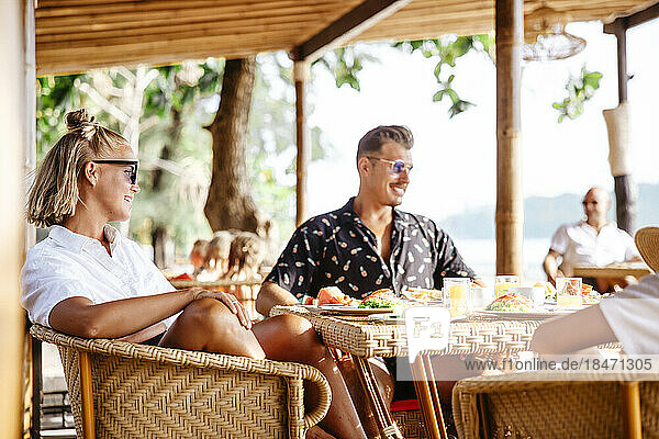 Lächelndes heterosexuelles Paar am Tisch sitzend beim Frühstück im Resort