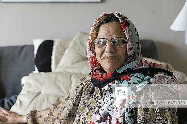 Porträt einer lächelnden reifen Frau mit Schal und Brille zu Hause