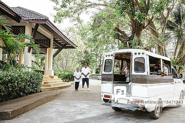 Männliche und weibliche Besitzer schauen sich Touristen an  die in einem Van am Urlaubsort sitzen