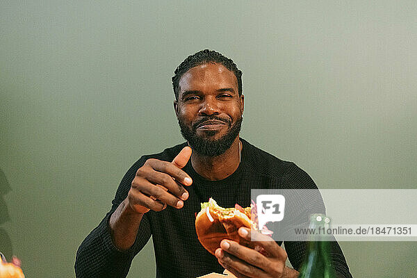 Portrait of smiling man eating burger at restaurant