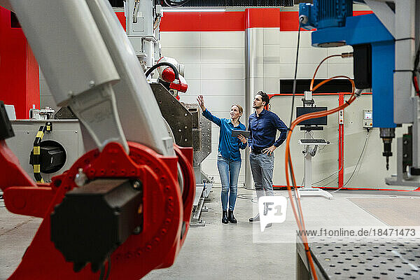 Engineer explaining colleague standing in robot factory