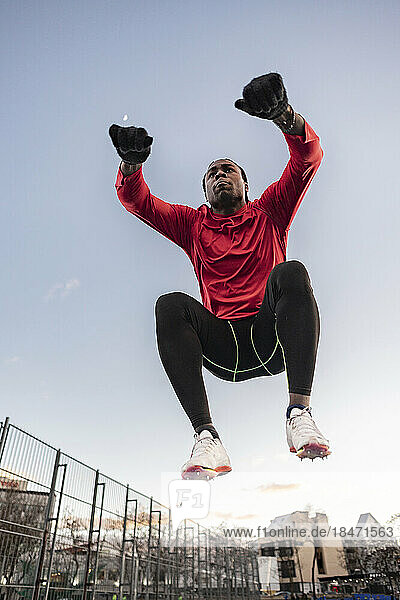 Man doing jumping squats at sports track