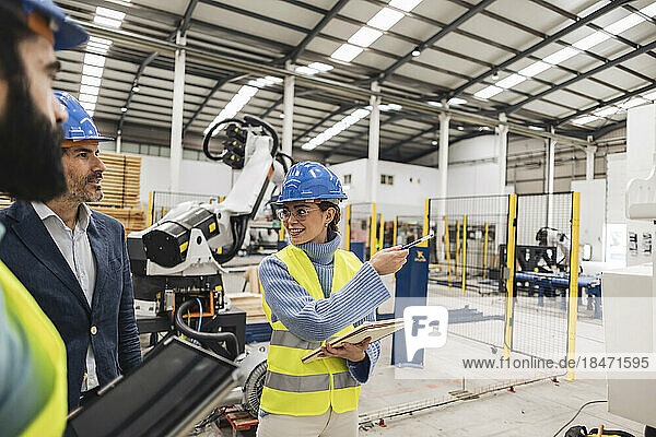 Smiling engineer gesturing colleagues in factory