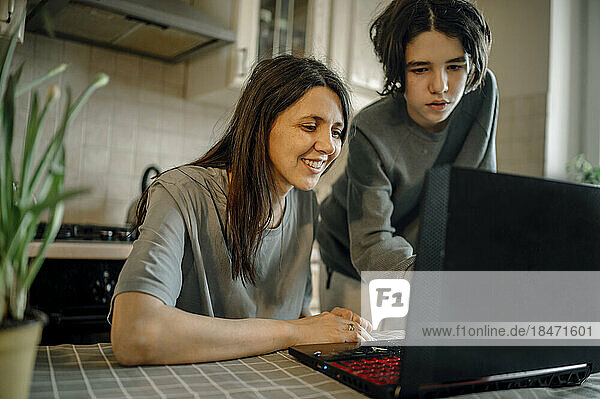 Son teaching laptop to mother at home
