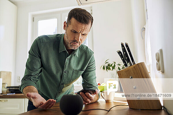 Man standing at home connecting smartphone to loudspeaker