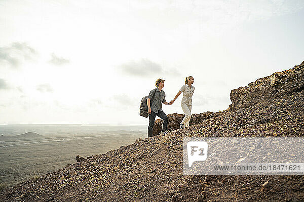 Young couple holding hands and hiking on mountain