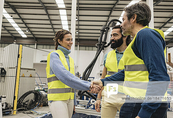 Engineer shaking hand with colleague in factory