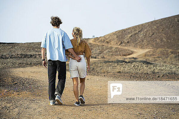 Boyfriend and girlfriend walking with each other on dirt road