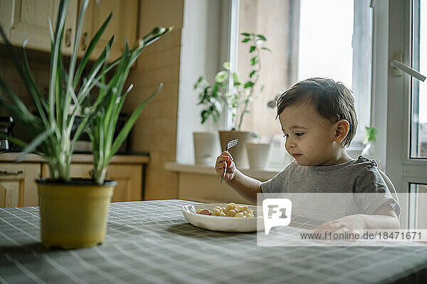 Boy eating pasta at table at home