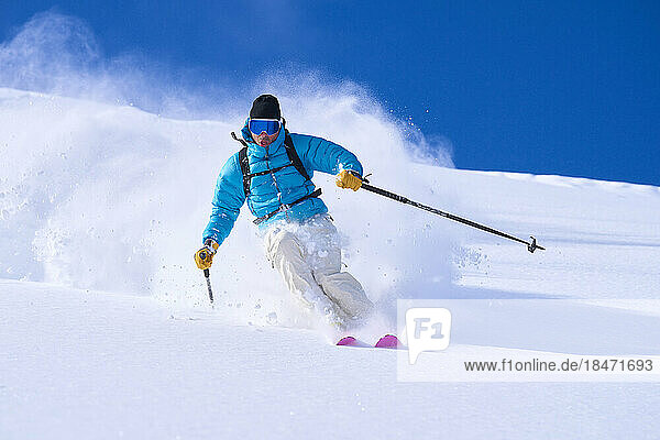Mature man skiing in powdered snow