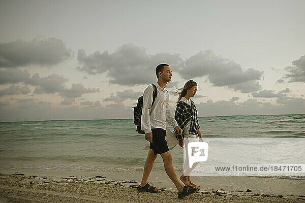 Young couple walking together near shore at beach