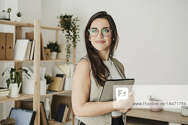 Thoughtful businesswoman wearing eyeglasses standing in office