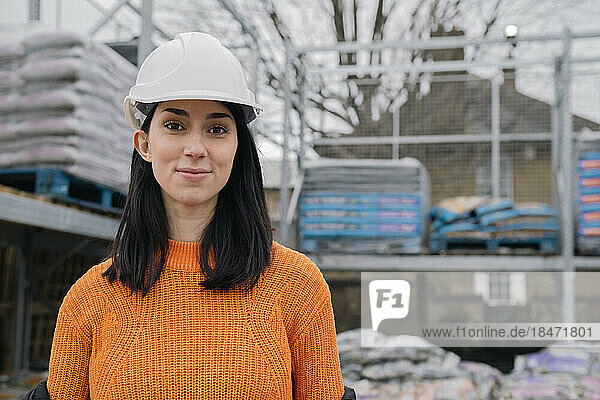 Confident woman wearing hardhat at construction site