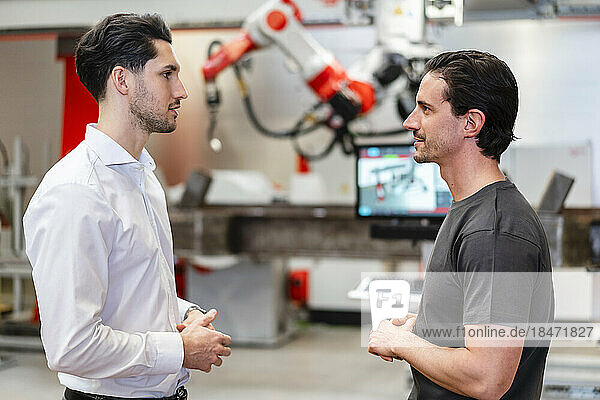 Technicians discussing with each other in robot factory