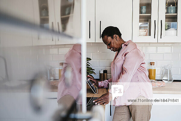 Lächelnde Frau benutzt Tablet-PC in der heimischen Küche