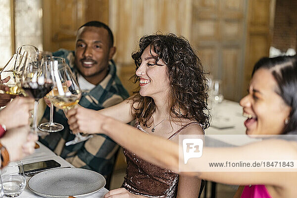 Friends toasting wineglasses at dinner party in restaurant