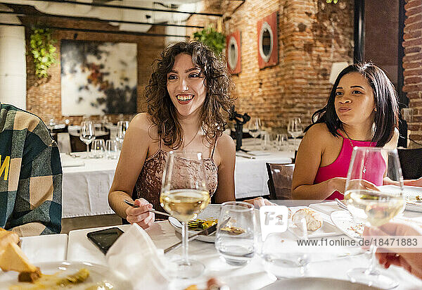 Happy women enjoying dinner with friends at restaurant