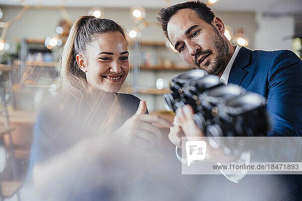 Smiling businesswoman with colleague discussing over lighting equipment